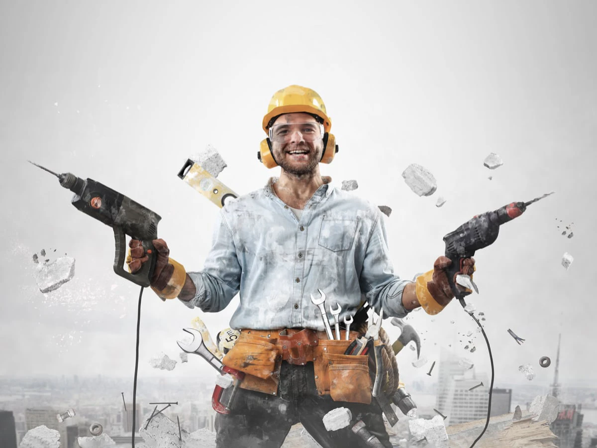 Person in Arbeiterkleidung mit zwei Bohrmaschinen in der Hand