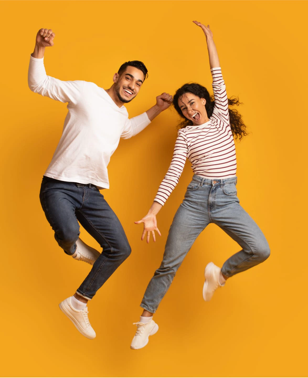 Zwei Menschen springen vor farbigem Hintergrund in die Luft